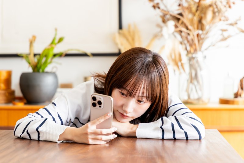 リビングでスマホを見る女性