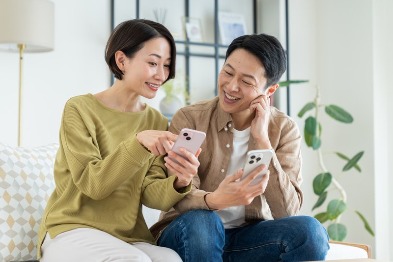 リビングでスマホを使うミドルの夫婦