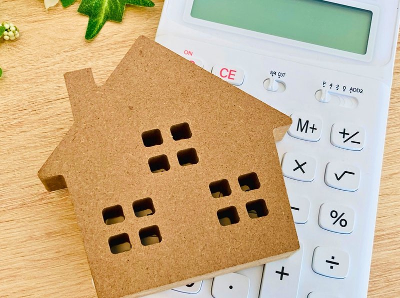 茶色い家の模型と白い電卓