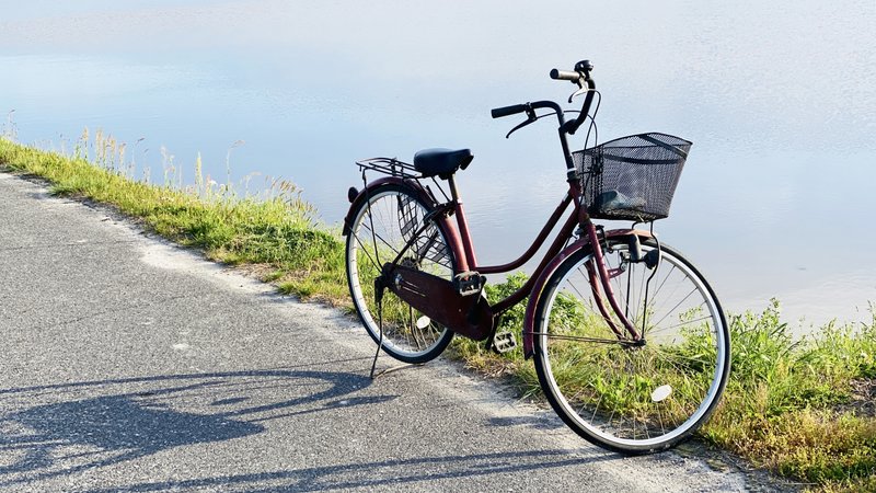 川辺の道に停まるカゴ付き自転車(作者: himawariin、M)